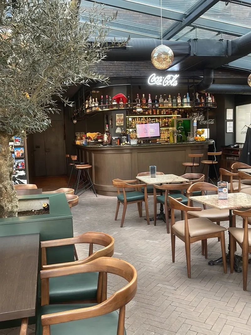 The bar and dining room with green chairs and olive trees
