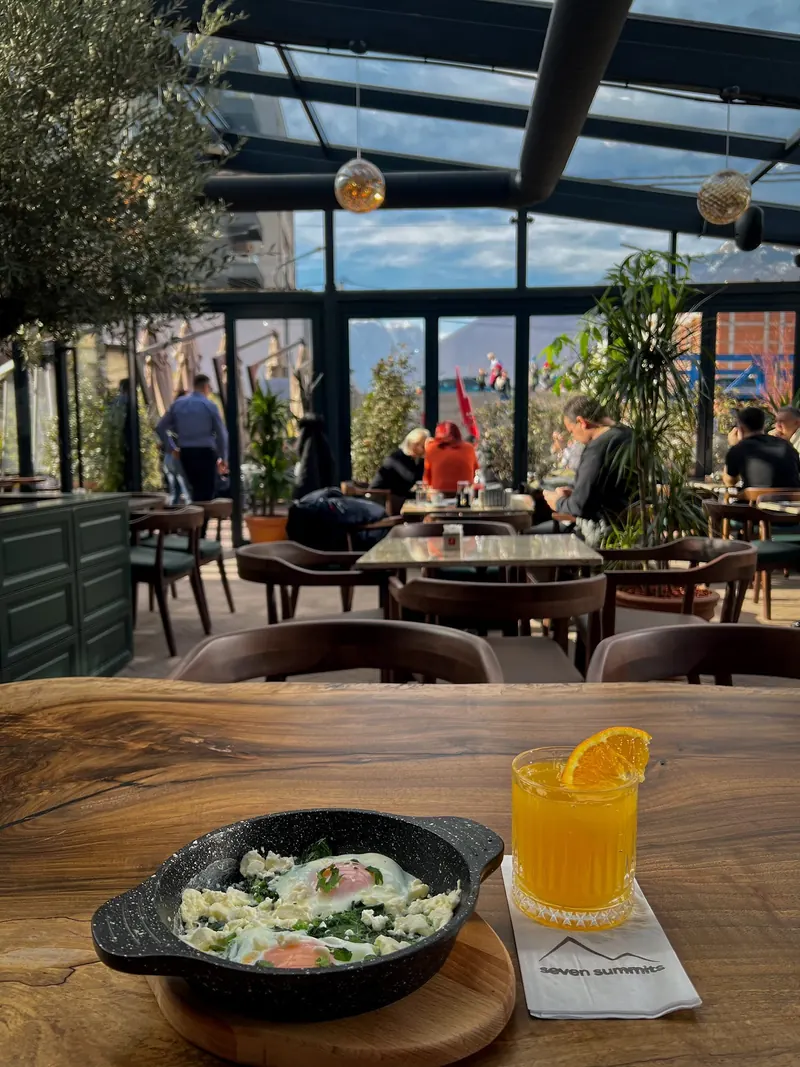 Breakfast pan and orange juice on the wooden table under the glass roof