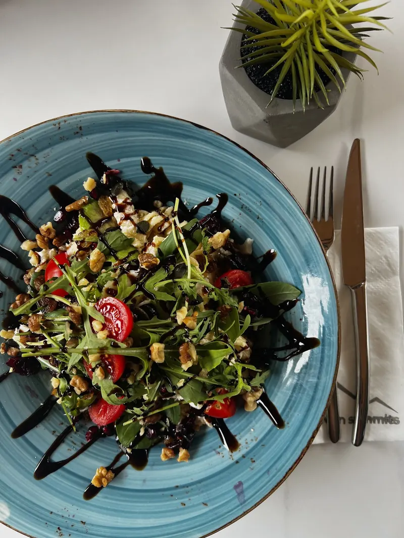 A salad with arugula, cherry tomatoes and balsamic on a blue plate