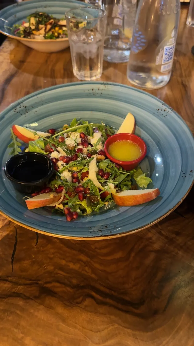 A salad with apple and pomegranate on a wooden table